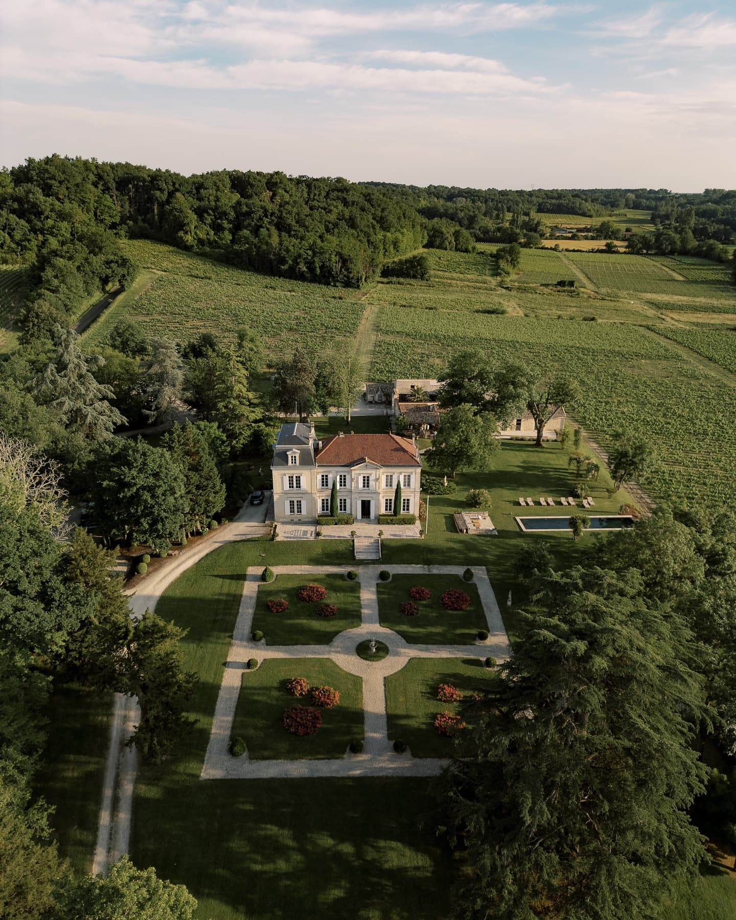 The château, its formal gardens and pool among the vineyards, seen from the air